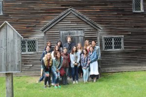 A group of students posting for a photo in front of a historic house. 