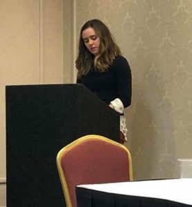 Jenna Burke speaking at a podium.